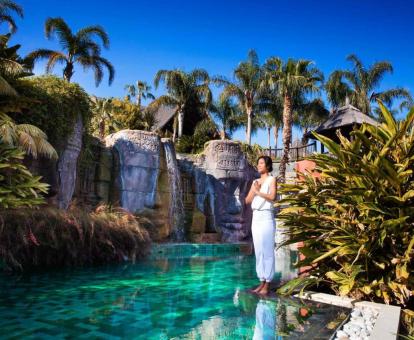 Mujer disfrutando de la paz de los jardines de este precioso hotel de estilo tailandés.