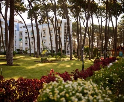 Jardines donde se ve el cesped y los arboles junto con un paseo rodeado de flores