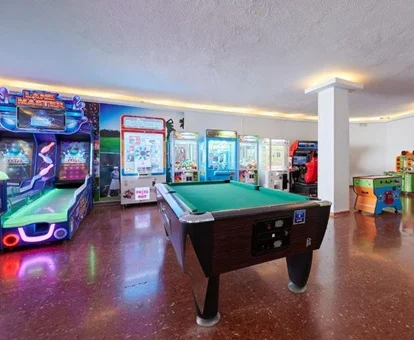 Zona de juegos para adultos y niños en el Alasun Marbella Park con minipista de bolos, billar y maquinas arcade.
