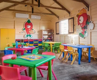 Zona del club infantil con decoración para niños en las paredes y unas mesas para hacer actividades infantiles