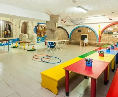 Zona de juegos infantil con mesas para actividades y amplio espacio para juegos.