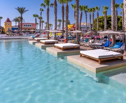 Zona chillout con camas y tumbonas para adultos con sombrillas y junto a la piscina