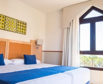 Habitación familiar con dos camas dobles y vistas a la piscina e instalaciones del hotel Playacanela