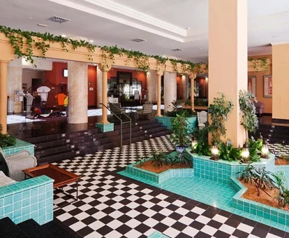 Hall del hotel Playacanela con sillones y un suelo de cuadros y pequeña piscina