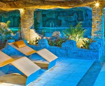 Dos tumbonas junto a una piscina y el jacuzzi del hotel Playacartaya