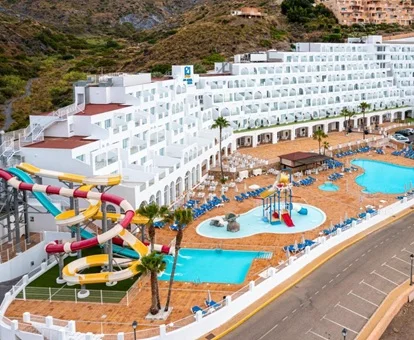 Vista zenital del hotel Playamojácar con las habitaciones en un edificio de color blanco, los toboganes junto a la piscina de adultos y la piscina infantil con toboganes infantiles.