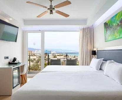 Vista desde la habitación para dos personas y dos niños con las dos camas dobles y las vistas al mar desde la terraza