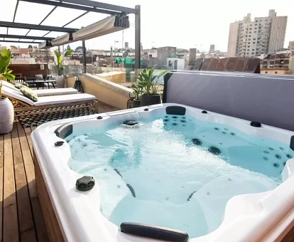 Jacuzzi enorme para parejas en la terraza amueblada de este apartamento con jacuzzi con vistas a la ciudad de Barcelona.