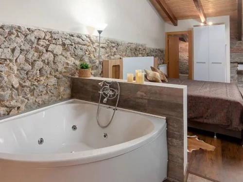 Foto del Jacuzzi en el apartamento de Santander con la cama detrás de la bañera de hidromasaje y junto a la chimenea