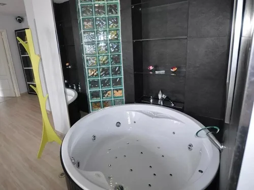 Jacuzzi circular para parejas enfrente de la cama con chorros de agua de hidromasaje