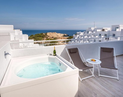 Foto de la Suite Junior Deluxe con bañera de hidromasaje donde tienes tumbonas y una terraza con jacuzzi privado con vistas al mar perfecto para parejas.