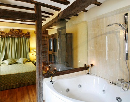 Foto de la Suite con la bañera de hidromasaje detras de un cristal en el baño y que se puede ver desde la cama de la habitación.