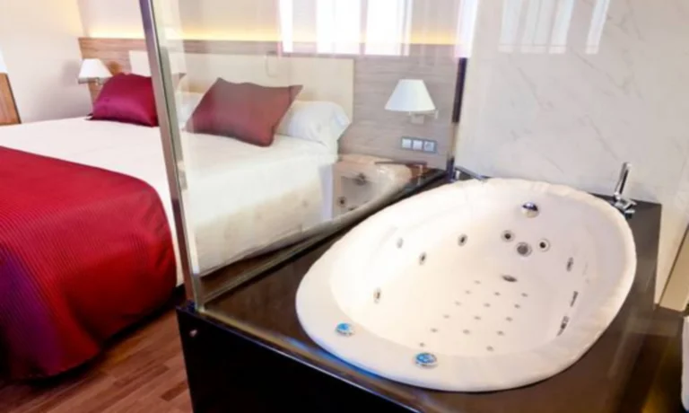 Foto de la Suite Superior donde tenemos una enorme jacuzzi privado en la habitacion junto a la ventana y cerca de la cama.