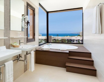 Bañera de hidromasaje circular privada que se encuentra en el baño y con vistas acristaladas al mar en las Suite