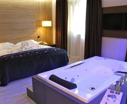 Bañera de hidromasaje privada junto a la cama en la Suite Syrah del hotel.