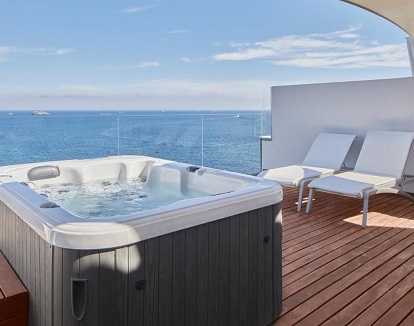 Fotos de la terraza con jacuzzi privado con vistas al mar junto a dos tumbonas para tomar el sol en la Suite Ático con vistas al mar y bañera de hidromasaje del Hotel Torre del Mar