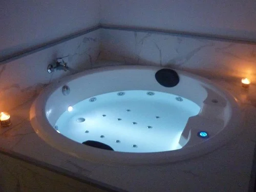 Foto del jacuzzi circular con luces y chorros de hidromasaje con dos velas en su borde en el apartamento La Gloria.