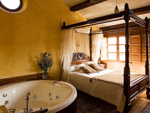 Foto del jacuzzi de forma circular que se encuentra junto a la cama en la Habitación Doble con bañera de hidromasaje con decoración rústica en madera y piedra