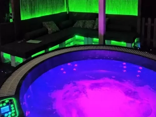 Jacuzzi exterior de la casa rural que se encuentra bajo un techado al aire libre y rodeado de mobiliario en una zona chill out