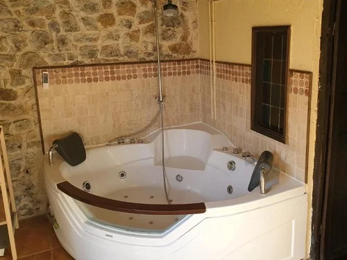 Jacuzzi para dos persones con chorros de hidromasaje en el rincón del baño de la casa rural Origenes.
