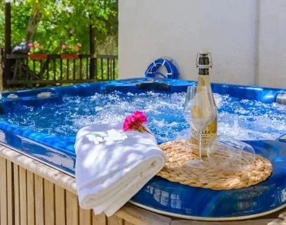 Foto del jacuzzi en el exterior con un toalla, un clavel, dos copas y una botella de cava en el jardín de El Tajil