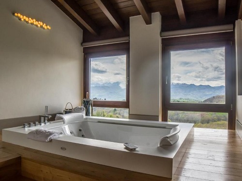 Jacuzzi rodeado de madera junto a la ventana con vistas al campo en la Suite Premium del hotel rural Puebloastur Eco Resort Wellness de Cofiño