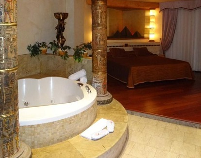 Foto del jacuzzi de forma circular que se encuentra bajo unos pilares cerca de la cama en la espectacular y romántica Suite del Motel Valle del Nilo.