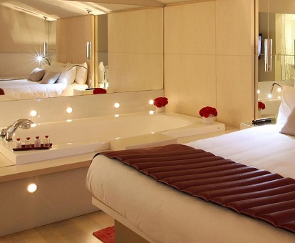 Bañera de hidromasaje junto a la cama y debajo del espejo en la Suite del Hotel Cram de Barcelona