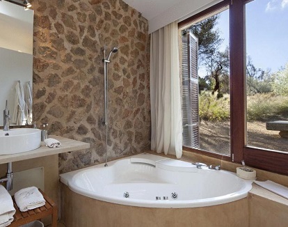 Foto de la bañera de hidromasaje privada con vistas al jardín a través del gran ventanal que tienes en el baño de la Suite.
