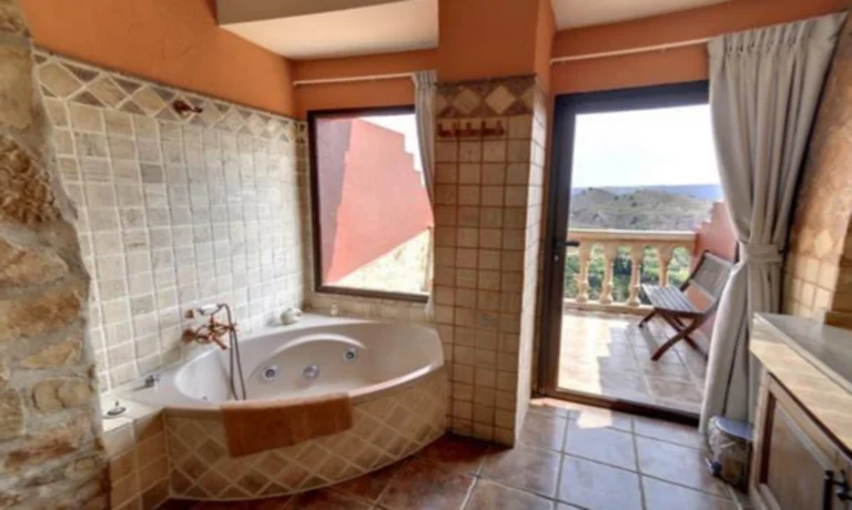 Foto Habitación Doble Superior donde se puede encontrar el jacuzzi junto a la ventana con vistas al campo y al salto de agua.