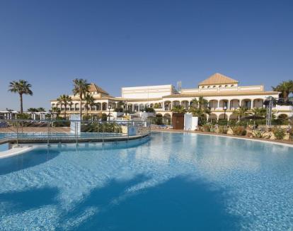 Foto del hotel y las piscinas al aire libre con vistas al mar.