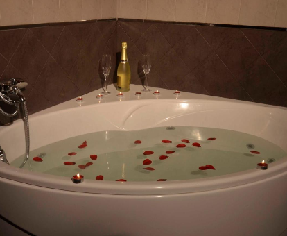 Foto de la bañera de hidromasaje con pétalos de rosa de los Apartamentos Spa Cantabria Infinita