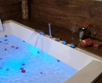 Foto del jacuzzi con pétalos de rosa y una botella de vino de la Casa Rural La Cantina