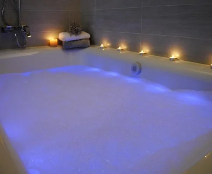 Foto de la bañera de hidromasaje con espuma y velas de las Casas de Outeiro