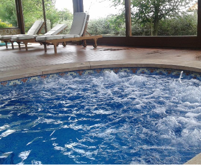 Foto de la piscina de hidromasaje cubierta con tumbonas de la casa rural Fuente de Güelo
