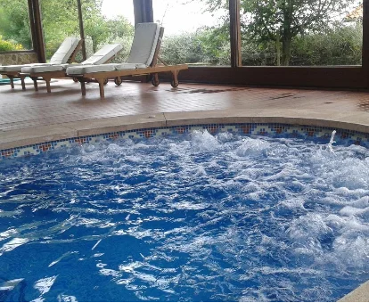 Foto de la piscina de hidromasaje cubierta con tumbonas de la casa rural Fuente de Güelo 
