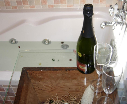 Foto de la bañera de hidromasaje con copa de champán que se encuentra en el Hotel Rural El Horno de Aliaga