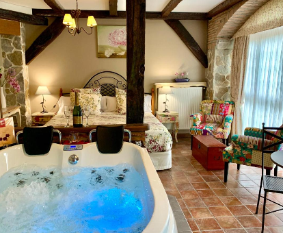 Foto de la habitación con bañera de hidromasaje al lado de la cama que se encuentra en La Casa Del Puente
