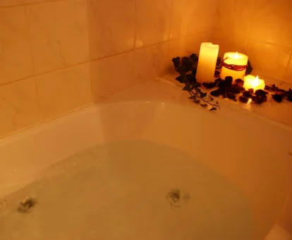 Foto de la bañera de hidromasaje con velas y pétalos de rosa que se encuentra en la Posada Rural Fontibre 
