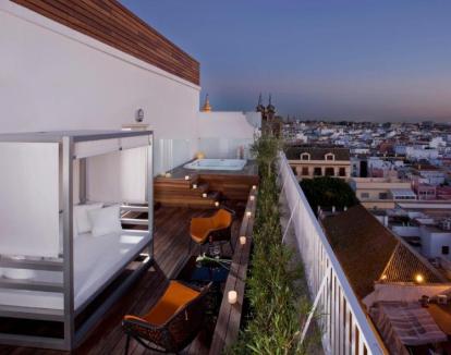 Foto de la Suite Ático con una amplia terraza con cama balinesa, jacuzzi privado y vistas a la ciudad.
