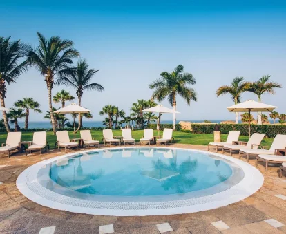 Bañera de hidromasaje rodeada de tumbonas y palmeras en el Iberostar Grand El Mirador - Adults Only