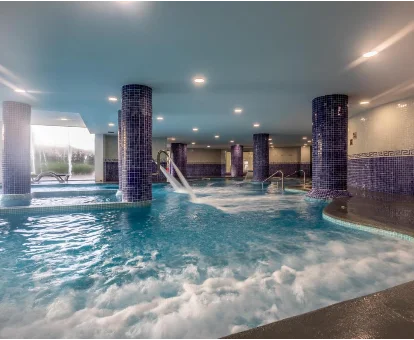 Piscina interior con chorros y regaderas de hidromasaje ubicada en el spa del Hotel Illot Suites en Cala Ratjada
