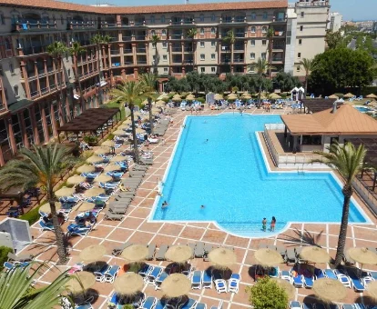 Piscina al aire libre rodeada de tumbonas y de las habitaciones del Ohtels Islantilla