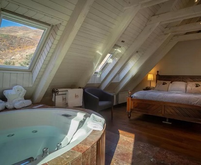Foto de la suite con bañera de hidromasaje donde vemos los techos de madera y el jacuzzi junto a la cama en esta suite del Hotel & Spa Casa Irene.