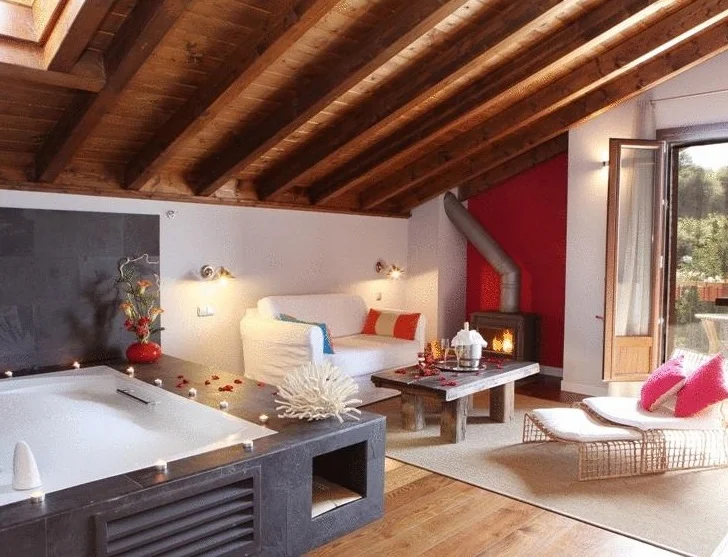 Foto del jacuzzi frente a la chimenea que hay en la Suite Junior decorada con techo de madera y suelo de madera. Un lugar muy romántico para ir con tu pareja que hemos encontrado en Navarra.