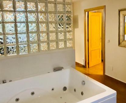 Foto de la bañera de hidromasaje de forma rectangular junto a un muro de cristal en el dormitorio de la Suite Exclusiva del hotel Chinchonspa