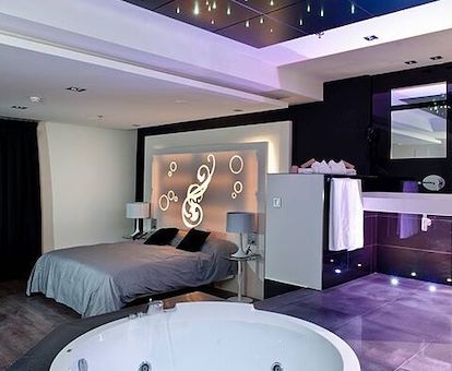 Foto del jacuzzi circular grande junto a la cama en una suite con decoración elegante y atrevida