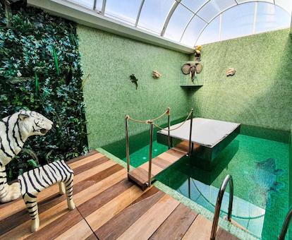 Foto de la piscina privada que se encuentra en la suite y donde tenemos una decoración en verde y una silla forrada con piel simulando ser un tigre