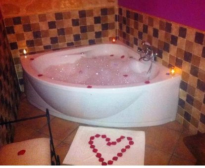 Foto de la bañera de hidromasaje con un baño de espuma y un corazón de pétalos de roda de la Casa Rural Las Albertas
