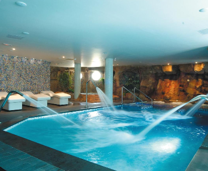 Foto del spa con piscina cubierta con chorros de agua y tumbonas que se encuentra en el Evenia Olympic Suites de Girona